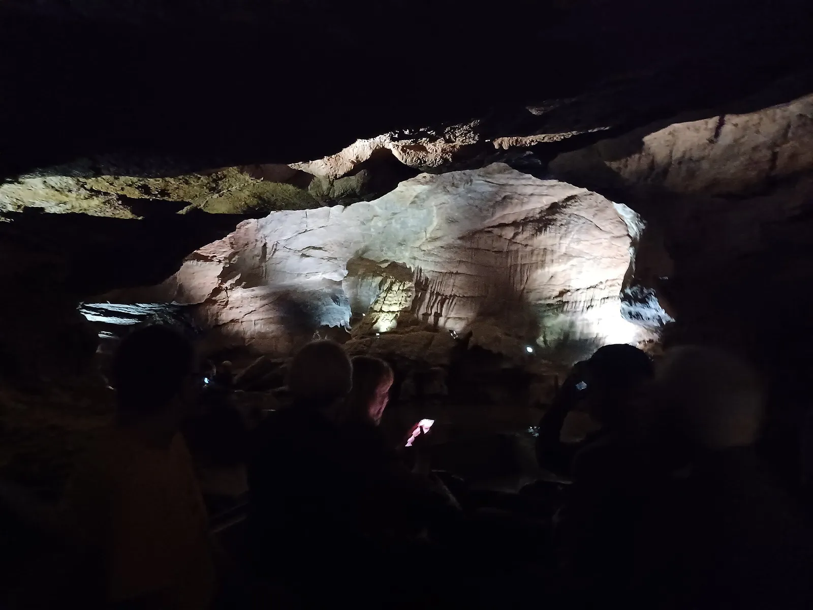 Interior de les Coves de Sant Josep, con la roca iluminada y visitantes a contraluz